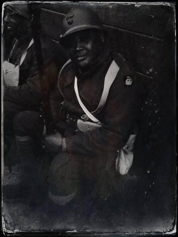 High-contrast, filtered modern color photograph, close portrait of a reenactor with a mustache and beard, holding a rifle in a trench setting.