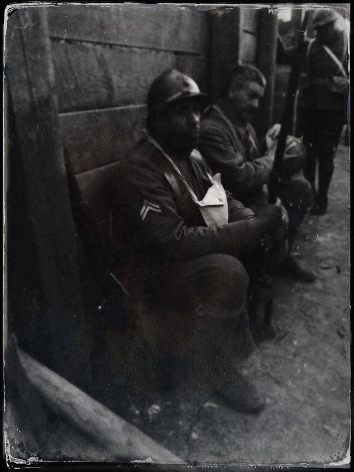 Filtered, aged-tone modern photograph of a reenactor seated in a trench, arm in a sling bandage.